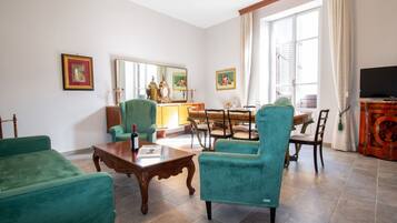 A living room with a dining area, a television, and a large window with curtains.