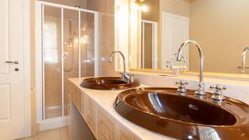 A bathroom with two sinks, a glass shower enclosure, and a large mirror.