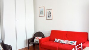 A room with a red sofa, a black chair, a white wardrobe, and two framed pictures on the wall. - Casa D'Amato - Salerno (Salerno)