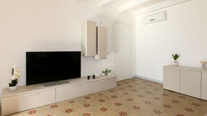 Un soggiorno moderno con TV a schermo piatto, mobili a incasso, ventilatore a soffitto e pavimento decorato.