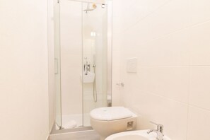 Un baño con cabina de ducha de vidrio, inodoro y lavabo con grifo.