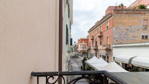 Uma rua estreita com edifícios de ambos os lados, uma pessoa caminhando e uma tenda branca.