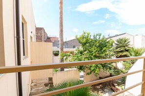 A courtyard with a palm tree, a staircase, and a view of neighboring buildings. - Xenia Boutique House 3 (Oristano)