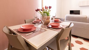 Tavola imbandita con piatti rosa, bicchieri e un vaso con fiori.