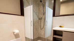 A bathroom with a glass shower enclosure, a toilet paper holder, and a vanity with a towel rack. - Cocco e Dessì Home- Angelica (ORISTANO)
