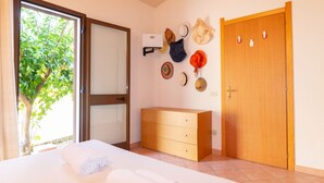 Een hotelkamer met een bed, een houten dressoir, een wandkapstok en een deur met een deurklink.