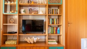 Een houten entertainmentkast met een televisie, boekenkasten en decoratieve voorwerpen.