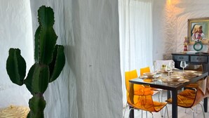 A dining area with a cactus, a table set for four, and a painting on the wall. - La Casa Del Sole- Luxury home (San Giovanni di Sinis)