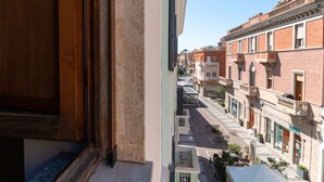 Un vicolo stretto fiancheggiato da edifici, cielo sereno e vista da una finestra con cornice in legno.