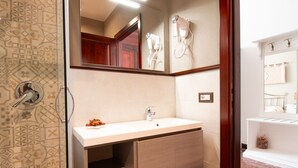 A bathroom with a shower, a sink, a mirror, and a towel rack. - Cocco e Dessì Home- Tamara (ORISTANO)