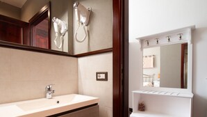 A bathroom with a sink, a mirror, a hairdryer, and a vanity. - Cocco e Dessì Home- Tamara (ORISTANO)