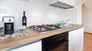 Une cuisine équipée d’une cuisinière à gaz, d’une machine à café, d’une bouteille de vin et d’un évier.