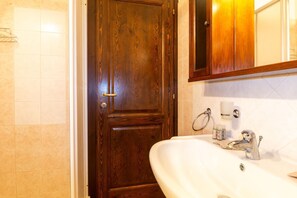A bathroom with a wooden door, a white sink, a mirror, and a towel rack. - Zenzerino Apartment-Cabras (Cabras)
