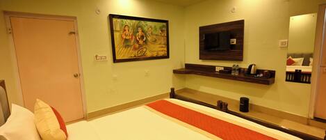 A hotel room with a bed, a painting on the wall, a TV, and a mirror.