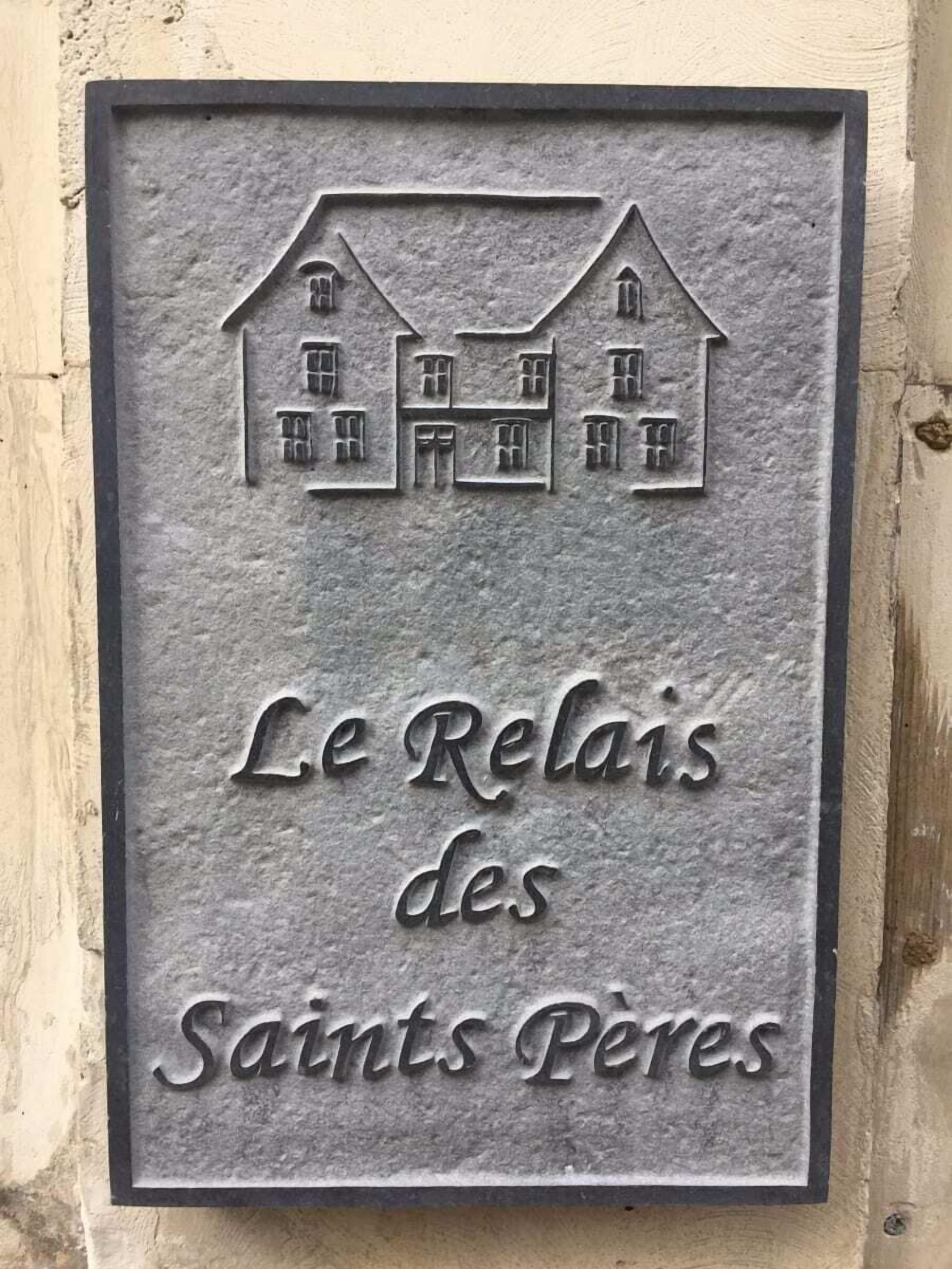 Une plaque en métal représentant une maison et portant l’inscription « Le Relais des Saints Pères ».