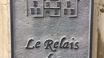 Une plaque en métal représentant une maison et portant l’inscription « Le Relais des Saints Pères ».