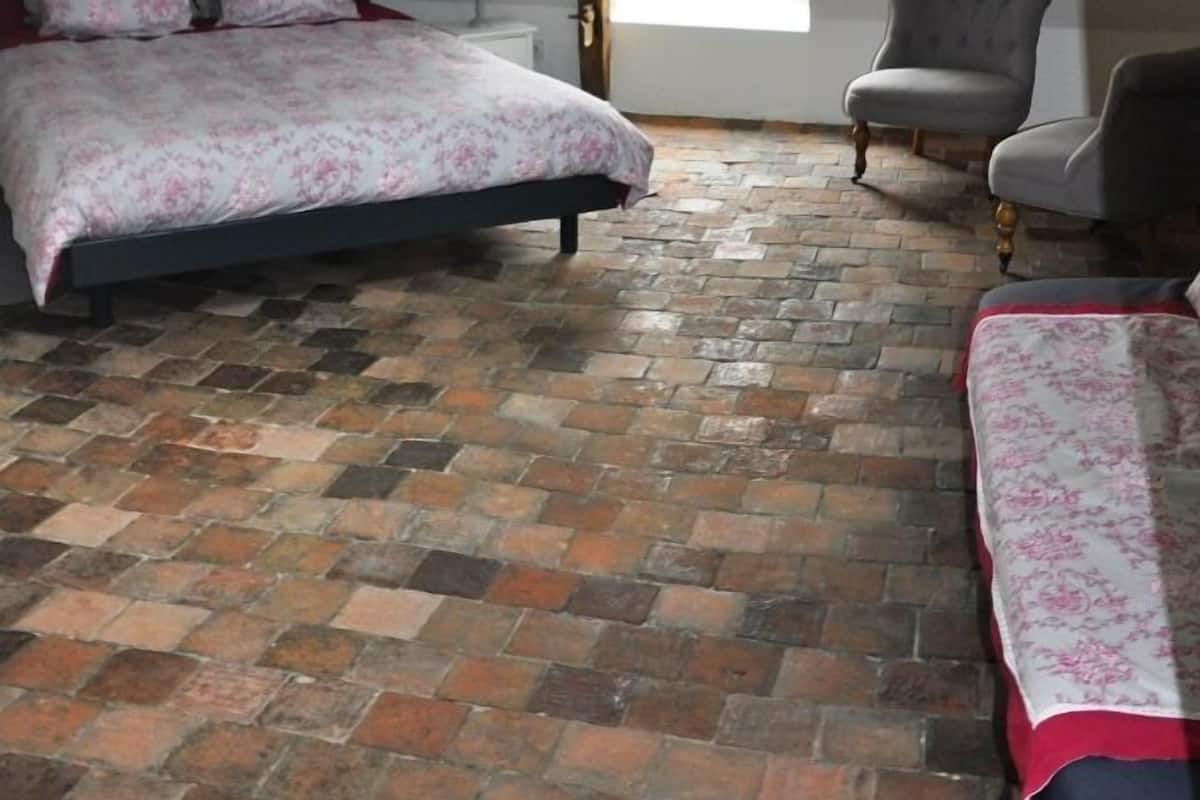 Een slaapkamer met een schuine kap, een bed met bloemenbedrukking, een stoel en een raam.