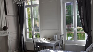 Een slaapkamer met een bed, een klein tafeltje met een waterkoker en uitzicht op groen.