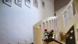 Een trap met witte spijlen, een radiator en een deur met een hartdecoratie.