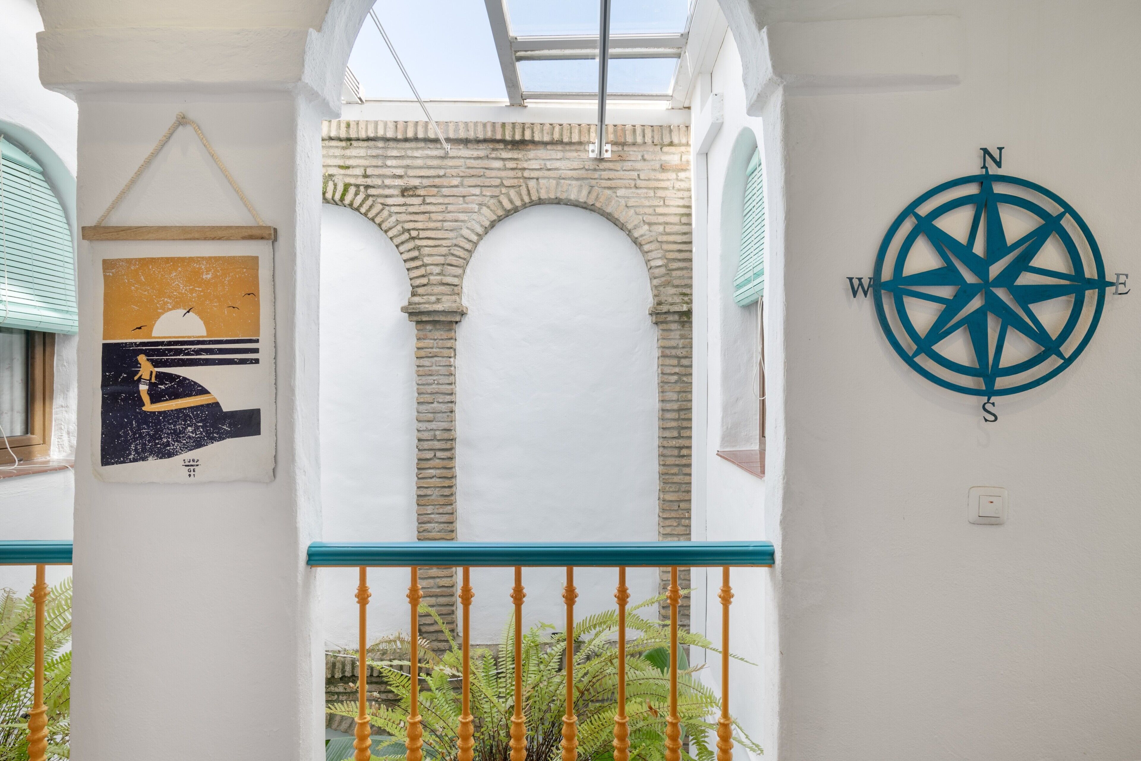 A white wall with a compass, a framed picture, and a stone archway.