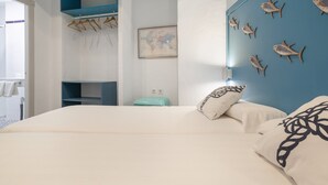 A bedroom with a bed, a blue wall with fish decorations, a map, and a hanging rack with clothes. - Room 'Hostal Santa Catalina 2' with Shared Terrace, Wi-Fi and Air Conditioning (Conil de la Frontera)