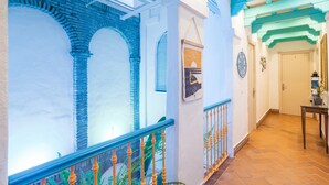 A corridor with a glass ceiling, a brick wall, and a wooden railing. - Room 'Hostal Santa Catalina 2' with Shared Terrace, Wi-Fi and Air Conditioning (Conil de la Frontera)