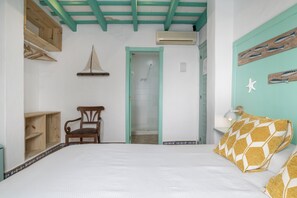 Ein Schlafzimmer mit einem Bett, einem hölzernen Stuhl, einer Tür zu einem Badezimmer und einer Wand mit einer Meerstern-Dekoration.