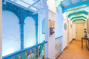 A corridor with a glass ceiling, brick arches, a wooden railing, and a tiled floor. - Room 'Hostal Santa Catalina 3' with Shared Terrace, Wi-Fi, and Air Conditioning (Conil de la Frontera)
