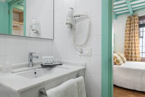 Ein Badezimmer mit Waschbecken, Spiegel, Fön und Handtuchhalter.