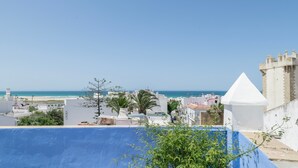 A coastal cityscape with a clear sky, a beach in the distance, and a prominent white tower. - Room 'Hostal Santa Catalina 4' with Shared Terrace, Wi-Fi and Air Conditioning (Conil de la Frontera)