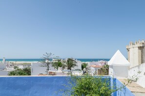 A coastal cityscape with a clear sky, a beach in the distance, and a prominent white tower. - Room 'Hostal Santa Catalina 4' with Shared Terrace, Wi-Fi and Air Conditioning (Conil de la Frontera)