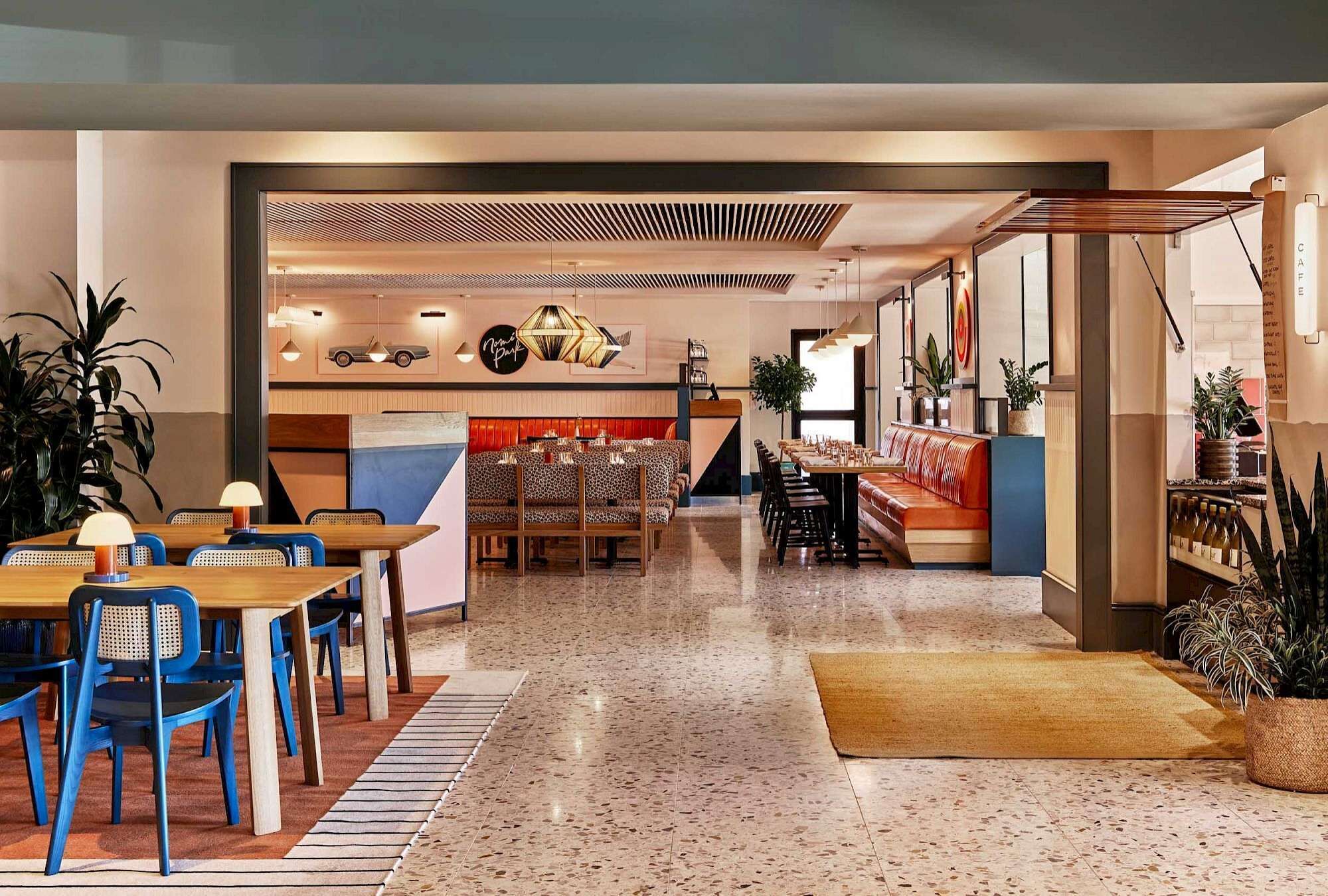 A modern restaurant with a central seating area, a bar, and a visible kitchen.