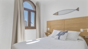 A bedroom with a bed, a window, a wall-mounted fish decoration, and a nightstand. - Room 'Hostal Santa Catalina 9' with Shared Terrace, Wi-Fi, and Air Conditioning (Conil de la Frontera)