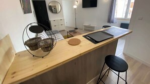 A modern kitchen with a wooden countertop, a round cork mat, and wicker baskets. - Le Chaleureux - Charmant T2 proche metro (Toulouse)