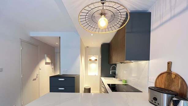 Uma cozinha moderna com bancada de mármore, forno embutido, torradeira e tábua de corte de madeira.
