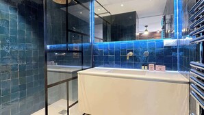 Casa de banho moderna com cabine de chuveiro em vidro, toucador branco e paredes com azulejos azuis.