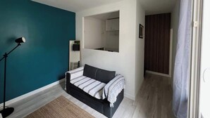 Een moderne slaapkamer met een bed, een staande lamp en een uitzicht op een badkamer door een geopende deur.