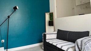 Een slaapkamer met turquoise wanden, een bed met behang, een vloerlamp zwart en een spiegel boven het bed.