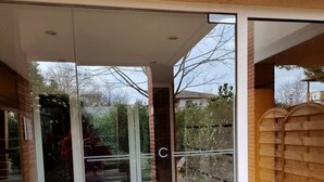 Ein moderner Eingangsbereich mit Glastüren, einem Fliesenboden mit geometrischem Muster und einer Backsteinwand.
