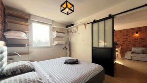 Ein modernes Schlafzimmer mit einem Bett, einer Pendelleuchte, einer Schiebetür und einer Ziegelwand.