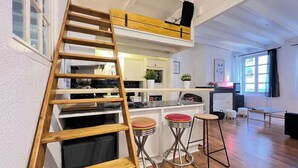 Eine moderne Küche mit einer Holzleiter, zwei Barhocker und einer Bar.