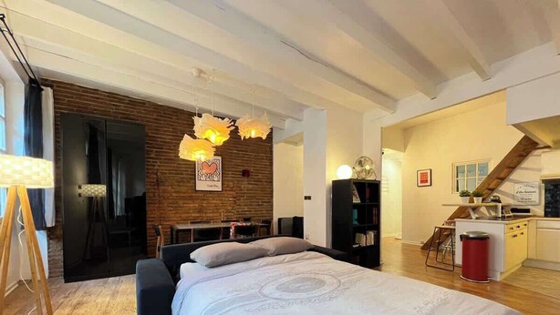 Ein modernes Schlafzimmer mit einem großen Bett, einem Schreibtisch und einer Küchenzeile.