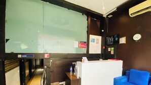 Een receptiegedeelte met een receptiebalie, een blauwe bank en een klok aan de muur.