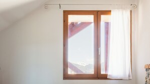 A bedroom with a large bed, a window with curtains, and a view of mountains. - Bright Chalet with mountain view terrace - duplex (La Salle-les-Alpes)