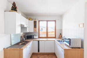 Una cocina compacta con gabinetes blancos, un microondas, un tostador y una estufa.