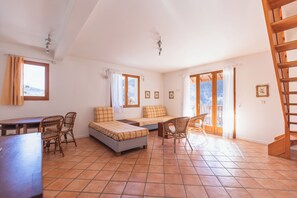 Una habitación amplia con cama, una mesa de comedor, sillas y una escalera.