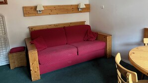 A cozy room with a wooden bed, a small wooden table, and a chair. - EXCEPTIONAL PRICE Méribel center ski in ski out with parking ski locker and balcony (meribel)