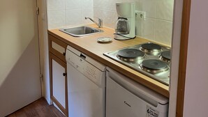 A compact kitchen with a microwave, coffee maker, sink, and dishwasher. - EXCEPTIONAL PRICE Méribel center ski in ski out with parking ski locker and balcony (meribel)