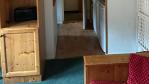 A narrow hallway with wooden cabinets on one side and a kitchen area on the other. - EXCEPTIONAL PRICE Méribel center ski in ski out with parking ski locker and balcony (meribel)