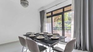 A modern dining area with a table set for six, a chandelier, and large windows with curtains. - Stayshort - Warm Spacious 3 Bedroom in The Greens That Sleeps 8 (Dubai)
